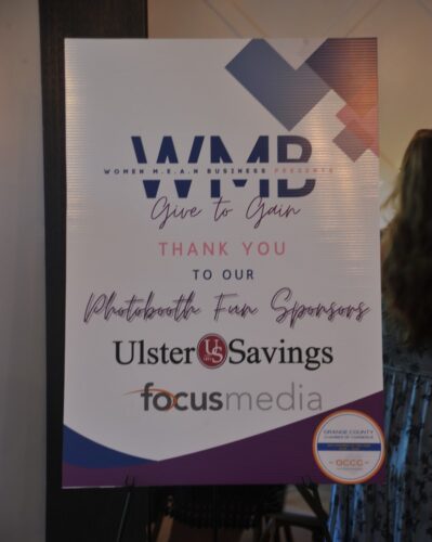 Event sponsor banner: 'Give to Gain' with Ulster Savings and Focus Media logos at an event, person partially visible on the right.