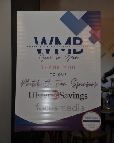 Poster board featuring a 'Give to Gain' slogan and sponsor logos, including Ulster Savings.